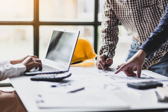 Group of architects meet together to design a map for the construction of a parking building project. Team of modern architects working on laptop in office.