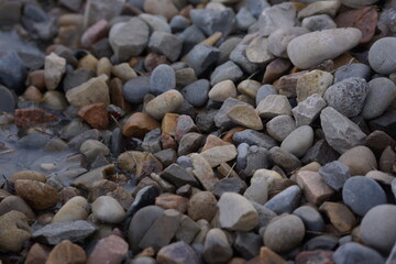 Macro of pile of multicoloured rocks with small puddle