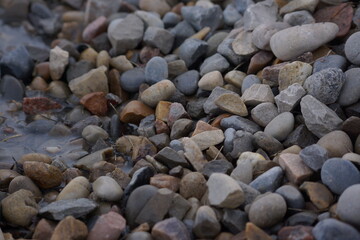 Macro of pile of multicoloured rocks with small puddle