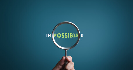 Magnifier focuses on word POSSIBLE side of the word IMPOSSIBLE. It is possible to motivational inspirational concepts. Unveiling the motivation concept. Blue background, flat lay. - obrazy, fototapety, plakaty