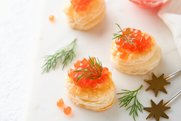 Salmon red caviar toast. Christmas canape or toast with red caviar on white plate on light background. Idea to xmas snack. Gourmet food. Texture of caviar. Seafood.
