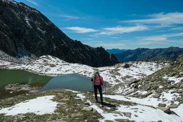 Hiker woman with scenic view of alpine lake Feldsee at Feldseescharte surrounded by majestic mountain peaks of High Tauern, Goldberg group, Carinthia Salzburg, Austria. Hiking trail in Austrian Alps