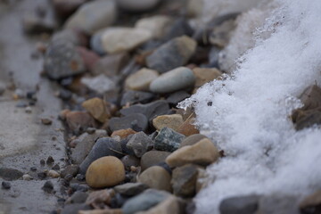 Multicoloured pebbles with patch of snow on it, macro