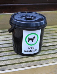 A dog waste bin or bucket on wooden slats, England, UK