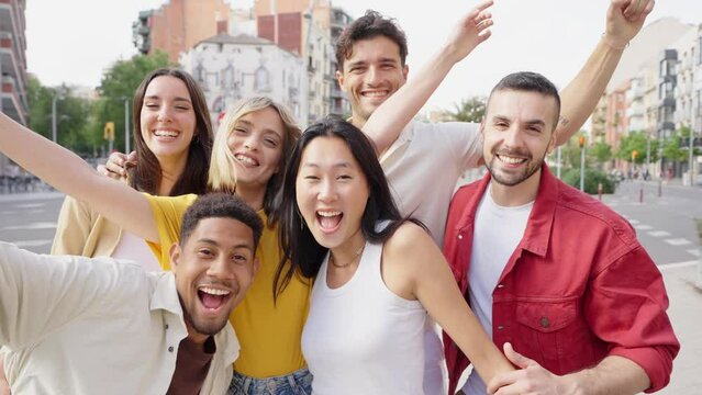 Multiracial young people smiling at camera outdoors - Group of happy friends having fun walking on city street - Youth community concept with guys and girls hanging outside - 4k video