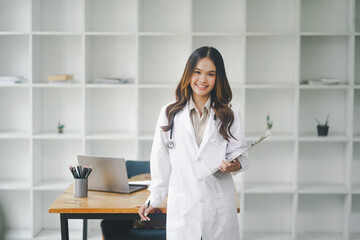 Medical concept of Asian beautiful female doctor in white coat with stethoscope, waist up. Medical student. Woman hospital worker looking at camera and smiling, studio,