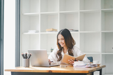 Beautiful young concentrated business woman wearing shirt using laptop while standing in modern workspace