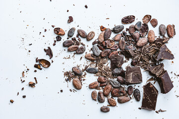 Cocoa beans and broken chocolate on white background. Top view copy space. Shallow dof