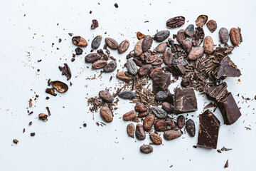Cocoa beans and broken chocolate on white background. Top view copy space. Shallow dof