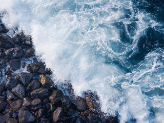 Rocky beach with Atlantic Ocean waves meeting with underwater sharp rocks. Blue sea with small...