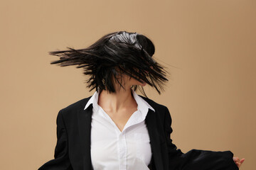 Happy dancing adorable brunet lady in classic suit throws head with flying hair posing isolated on...