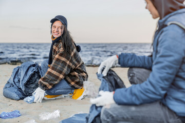 Volunteers cleaning plastic at the beach. Plastic pollution contamination of the coastline. Eco-activists collecting rubbish together, saving environment