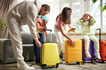 Family prepare for adventures while closing bags with luggage in living room at home. Holidays and vacations together. Concept of tourism, travelling agencies, relaxation. Ad
