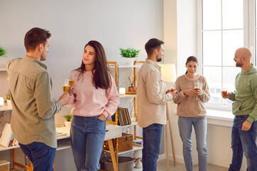 Happy diverse group of friends or colleagues engages in communication during a celebration party or business event at home or office. With glasses of champagne or wine in hand.