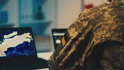 Ukrainian military man working on laptop, assessing Russia security threats