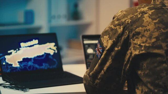 British intelligence officer working on laptop studying satellite data on Russia