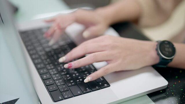 Close-up image capturing the hands of a person swiftly typing on a black computer keyboard in an office setting.