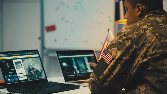 U.S. soldier analyzing satellite data on laptop, studying military targets