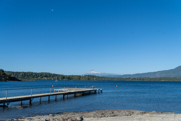 Fototapeta premium A serene summer day at a vacation lake. View of the dock with the volcano in the background.