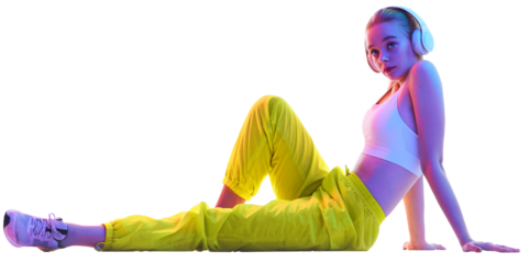 Side view portrait of young girl sitting on floor in trendy sport outfit and headphones looking away in neon against transparent background. Concept of sport, fashion, active lifestyle, youth. Ad