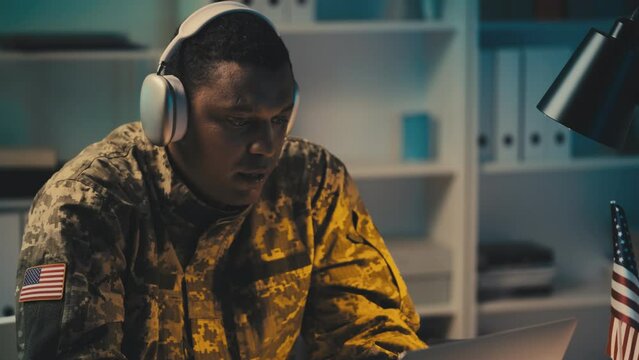 American military officer in earphones having work call consulting allies online