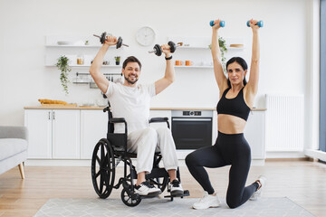 Portrait of physiotherapist or wife in sportswear and adult man with a disability in wheelchair...