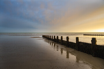 Sunset on Felpham beach on a winter evening, West Sussex, England. View of the wooden groynes.
