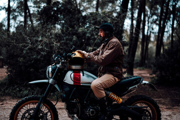 Fototapeta na wymiar Hombre moreno con moto dentro de un bosque posando y montando por terreno silvestre