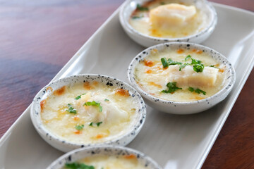 Baked scallop with cheese in mini bowl.