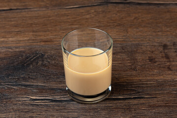 Glass with original Irish cream liqueur on a wooden table.