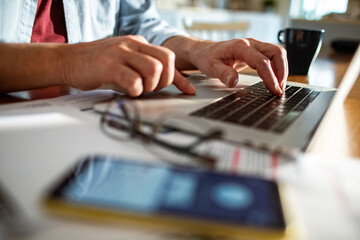 Close up of a man typing on the laptop doing online banking