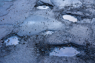 Potholes on the road after frost in winter in spring