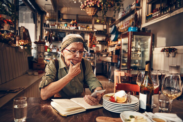Senior waitress doing expenses at a restaurant table
