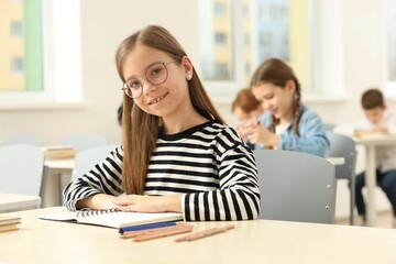 Fototapeta premium Portrait of smiling little girl studying in classroom at school