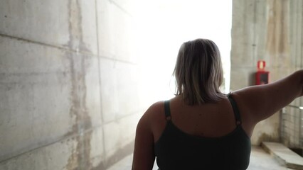 Smiling and curvy young woman doing exercises with dumbbells, during weight loss training. Active athlete and exercise routine to lose weight.