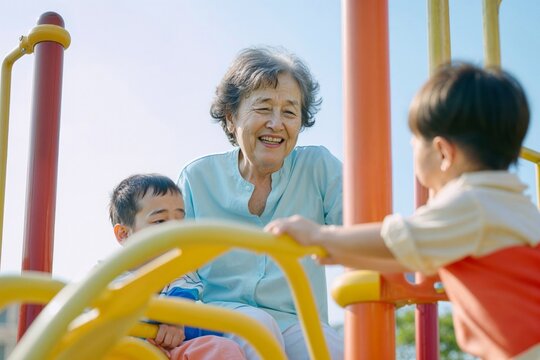 Active Senior Asian Woman Enjoying Time With Grandchild at Playground. Joyful Grandmother and Boy Engaging in Outdoor Play, Embracing Generational Bond