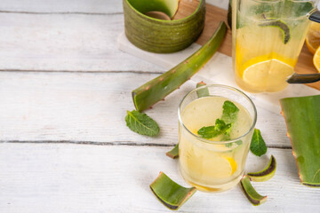 Aloe lemonade, homemade detox drink with lemon, aloe vera and mint on white wooden background copy space