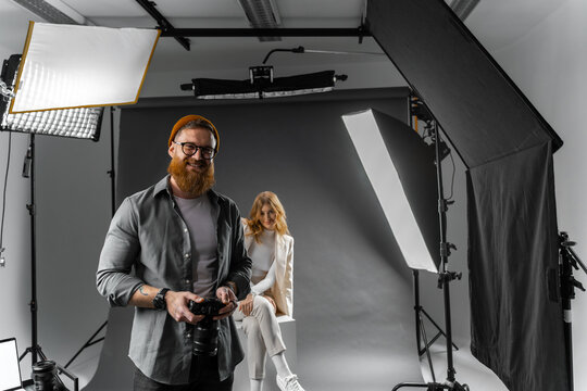 Focused male photographer using digital camera at photo shoot in studio