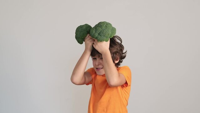 child holds broccoli over their head, their expression a mix of playfulness and reluctance. common childhood confrontation with healthy foods and the imagination used to make it fun.
