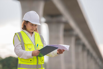 An Asian female engineer works at a motorway bridge construction site,Civil worker inspecting work...