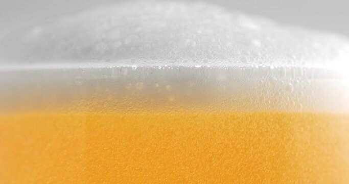 Super slow motion macro of fresh cold bio organic brewed beer in cool transparent glass with white bubbles foamy froth is going at 1000 fps.