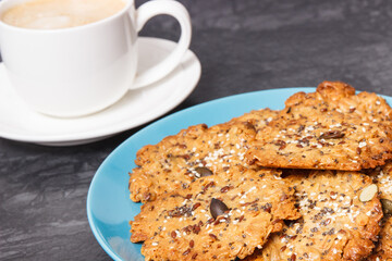 Cup of white coffee and fresh baked oatmeal cookies with honey and healthy seeds. Delicious crunchy dessert