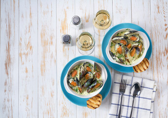 Cream soup with mussels and white wine on a white wooden table copy space for text.