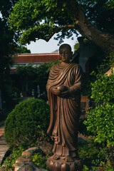 Wooden statue of a buddha in a green garden giving the emotion of tranquility