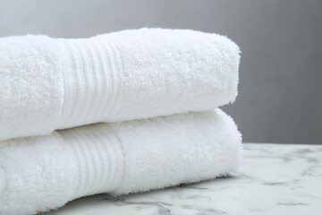 Folded terry towels on white marble table, closeup