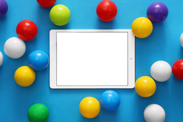 Modern tablet and balls on light blue background, flat lay. Space for text