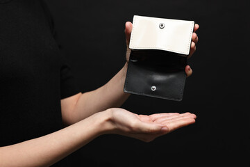 Woman with empty wallet on black background, closeup