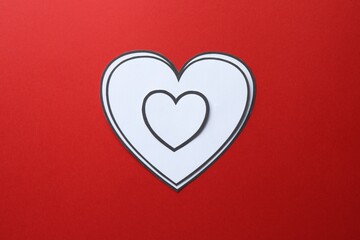 Paper hearts on red background, top view