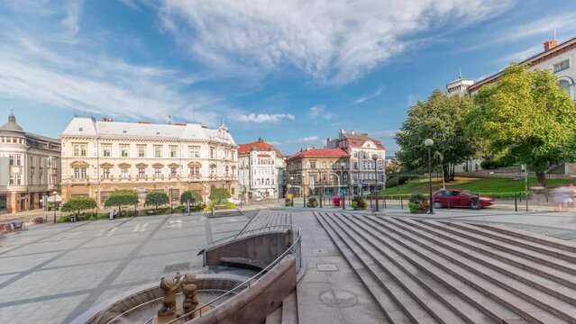 Panorama showing Sulkowski Castle and fountain on Chrobry Square in Bielsko-Biala timelapse, Poland. Historic buildings around. People walking and sitting in cafe. Clouds on a blue sky