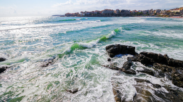 sozopol, bulgaria - 09 aug 2015: cityscape of the old town at the sea. waves crashing on the rocky coast in morning light. beautiful travel destination